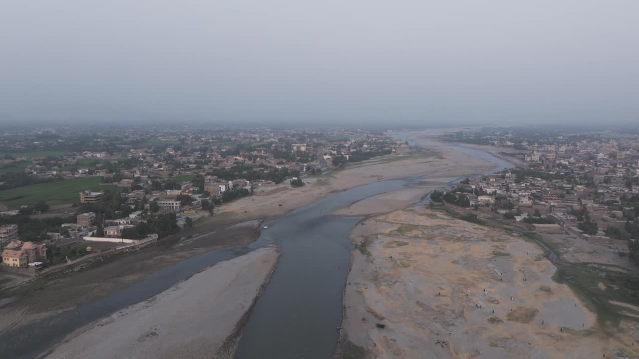 Jalalabad, Nangarhar, Afghanistan. Drone Aerial View of Kabul River and Buildings on Riverbanks, misty gloomy vibe