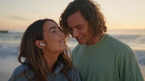 singende frau genießt musik mit ihrem freund am sonnenaufgangstrand. liebende haben spaß