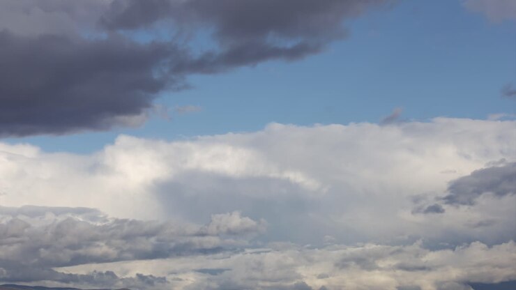 White clouds cover the blue sky, then get darker and dissipate
