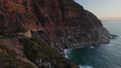 Vista-Panorámica-De-Chapman&#39;s-Peak-Drive-Durante-La-Puesta-De-Sol-En-Ciudad-Del-Cabo,-Sudáfrica---Disparo-De-Un-Dron