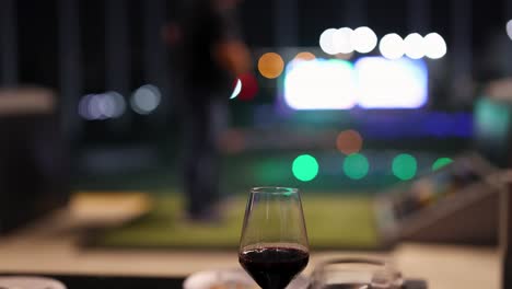 wine glass foreground, golfing activity in background