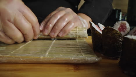 close-up of hands making sushi with a bamboo rolling mat