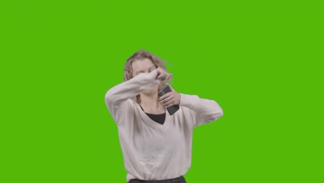 studio shot of young woman listening to music on mobile phone and dancing against green screen 6