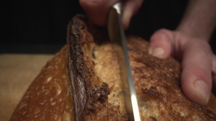 Slow motion macro shot of chef cutting freshly baked
