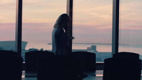 silhouette-business-woman-using-smartphone-talking-to-client-financial-advisor-negotiating-deal-sharing-expert-advice-having-phone-call-working-late-in-office-looking-out-window-at-sunset