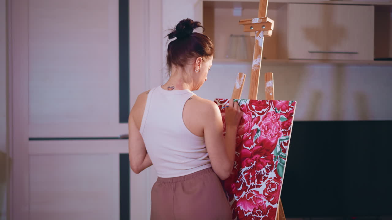 Female Artist In Calm Studio Painting Flowers, Young Woman Engaged In Peaceful Floral Painting In Studio, Youthful Woman Skillfully Paints Floral Designs In Tranquil Home Studio Setting