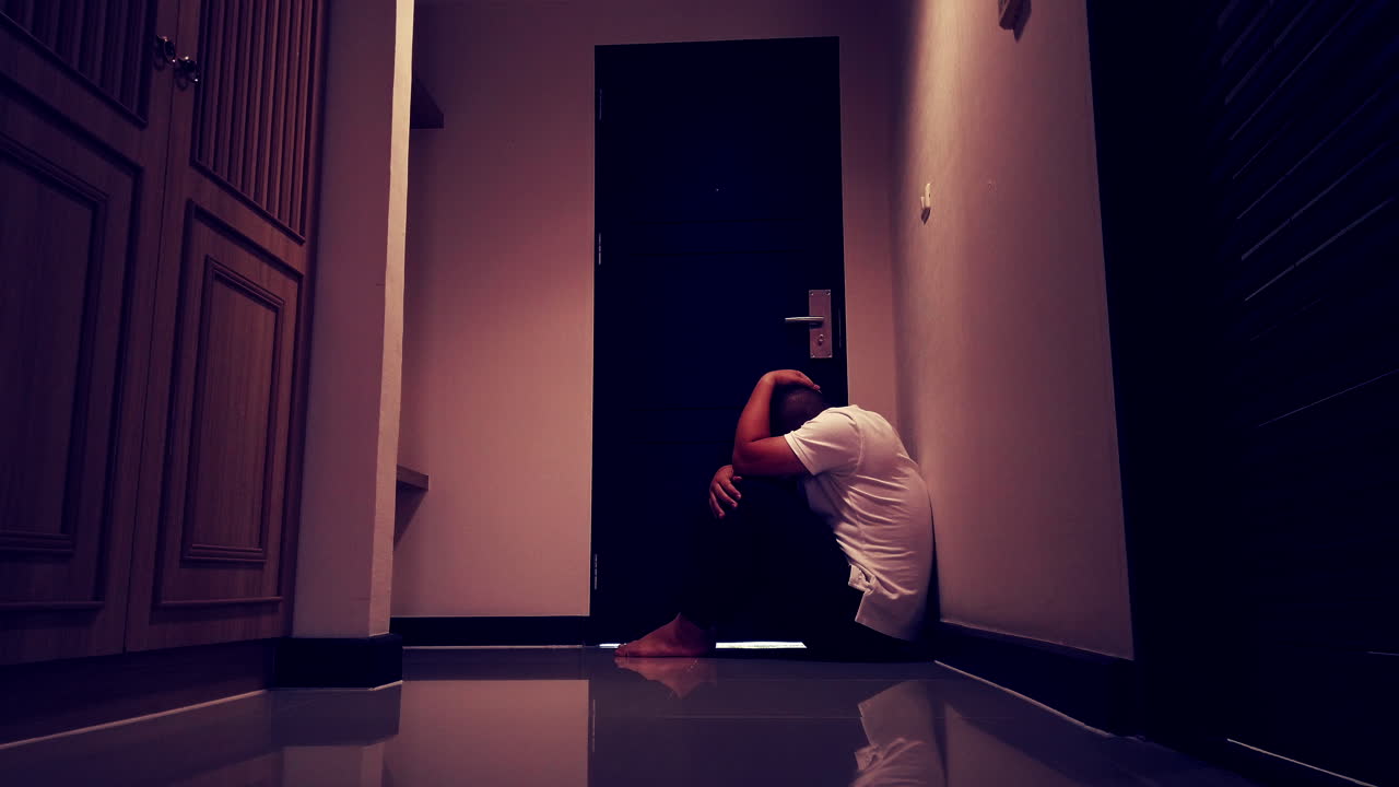 슬픈 남자는 그의 아파트 벽 모퉁이에 서서 손으로 얼굴을 가리고 있다