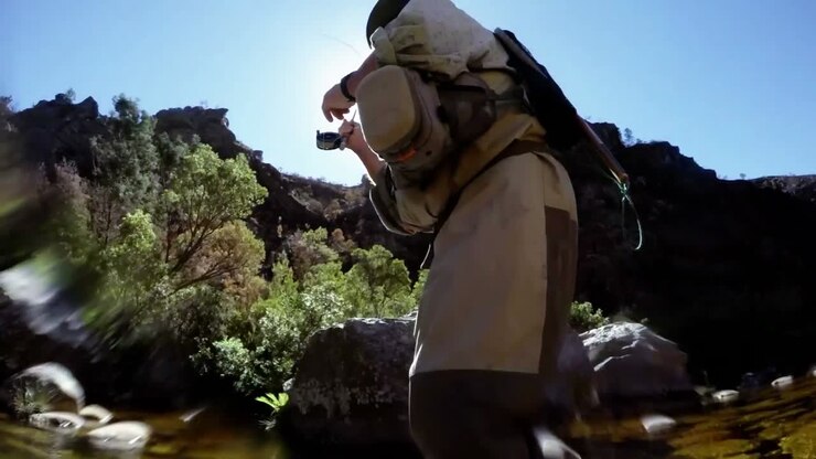 Pescador practicando pesca con mosca en un río.