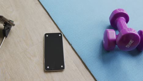 video of weights, mat and smartphone lying on floor