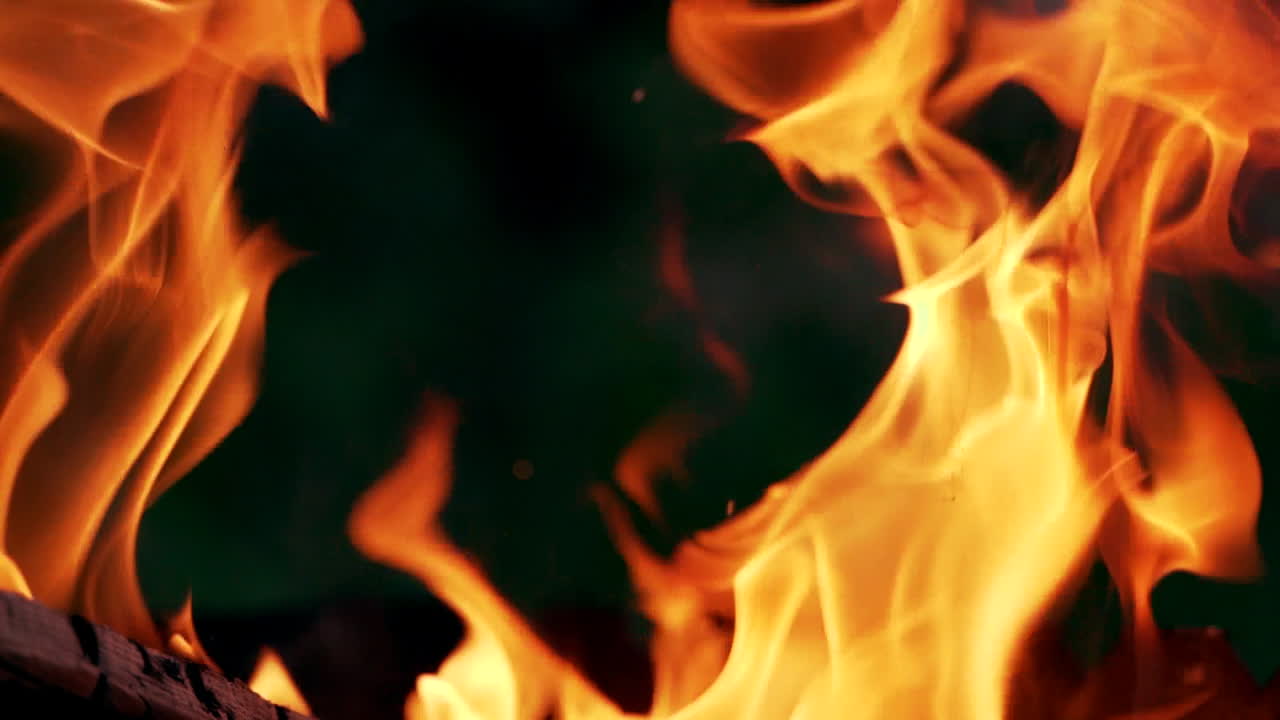 Close-up view of fire flame in darkness. Bright flame of twisting tongues from fire on black background.