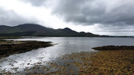 A-4K-rising-Drone-shot-of-Killmackogue-Harbour-with-a-speed-boat-at-Lauragh,-Co-Kerry,-Ireland