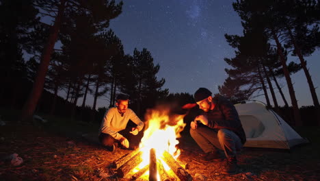 two men relaxing around a campfire under the stars