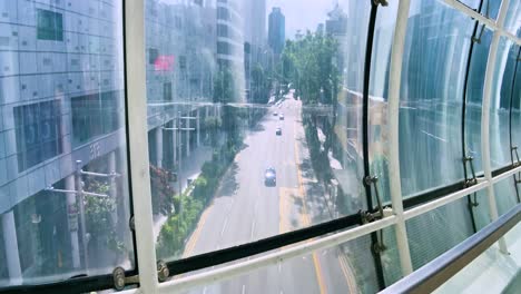 view of orchard road through glass wall of orchard gateway bridge in singapore