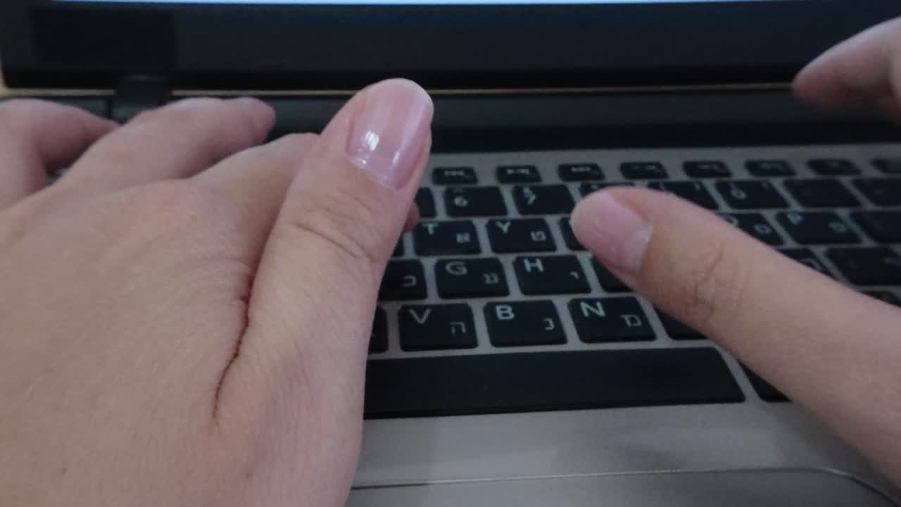 Front view of student's hands typing on a laptop keyboard. E-learning, research, or academic