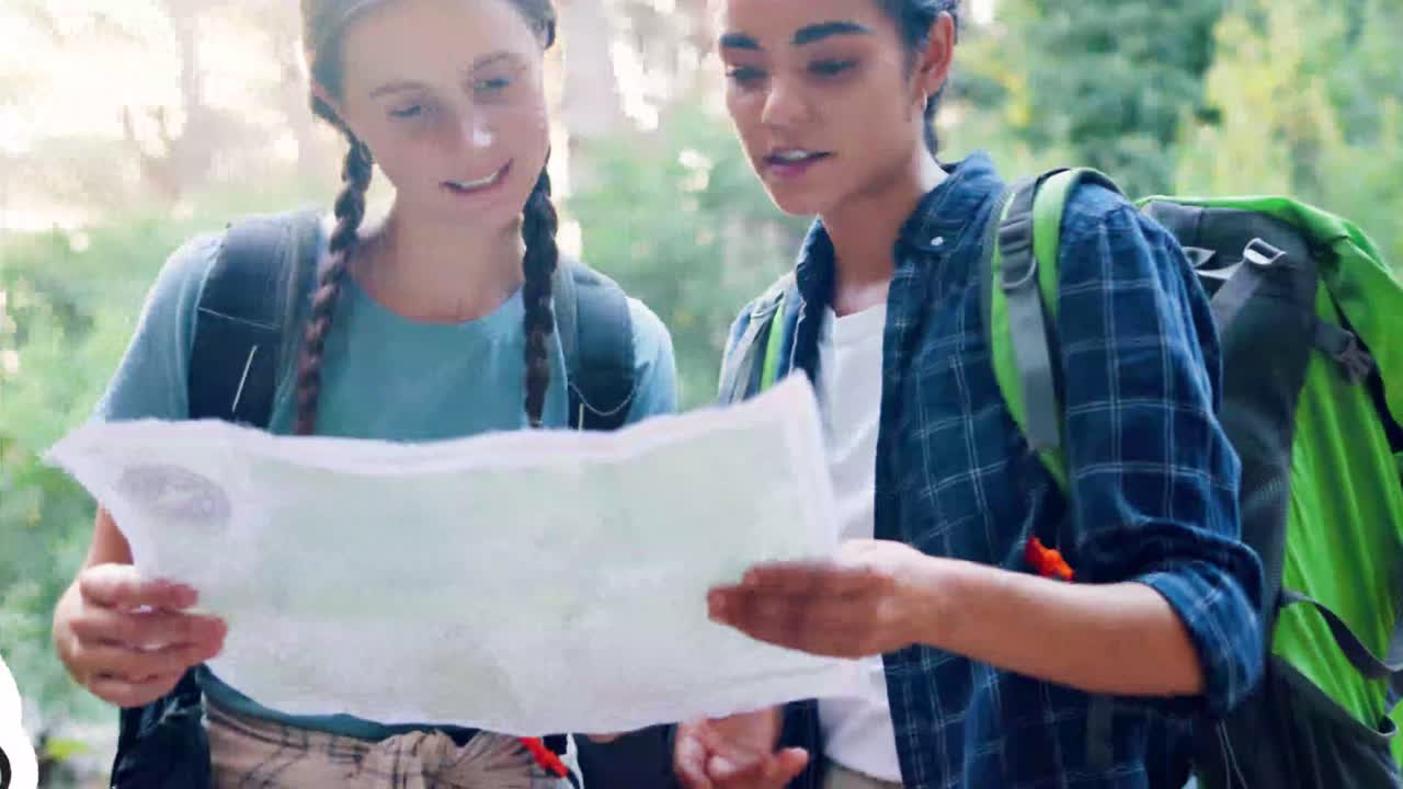 Two Young Women Hikers Looking at a Map in the Forest
