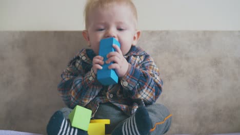 cute boy plays with bright cubes sitting on large soft bed