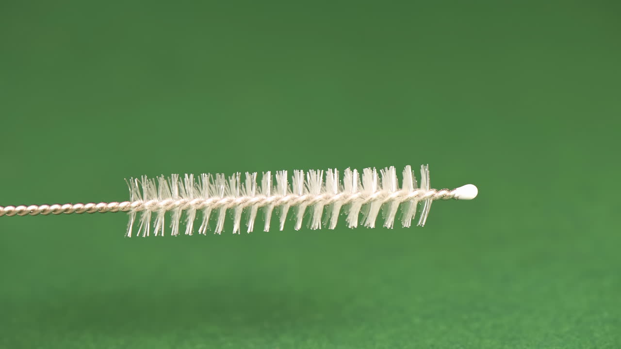 Bamboo straw cleaning with a brush on a green background