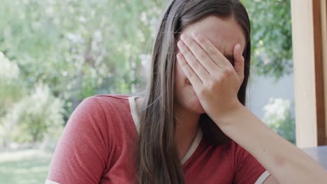 Sad-caucasian-teenage-girl-covering-her-face-alone-and-crying-in-slow-motion