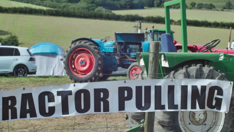 tractor tirando de la señal en la valla de alambre con tractores viejos dentro