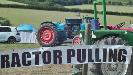 tractor pulling sign on wire fence with old tractors inside