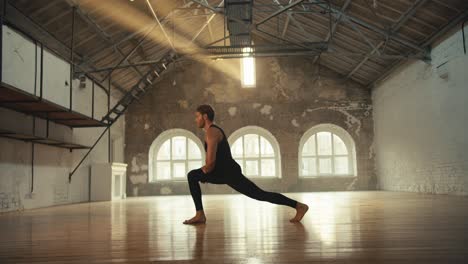 a man in a sports summer uniform does stretching at a yoga training in a sunny brick hall