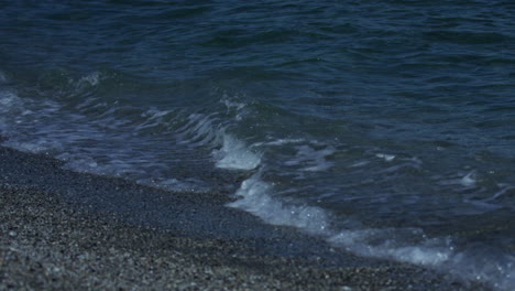 small waves roll in on a pebble beach in marbella spain, 4k slow motion