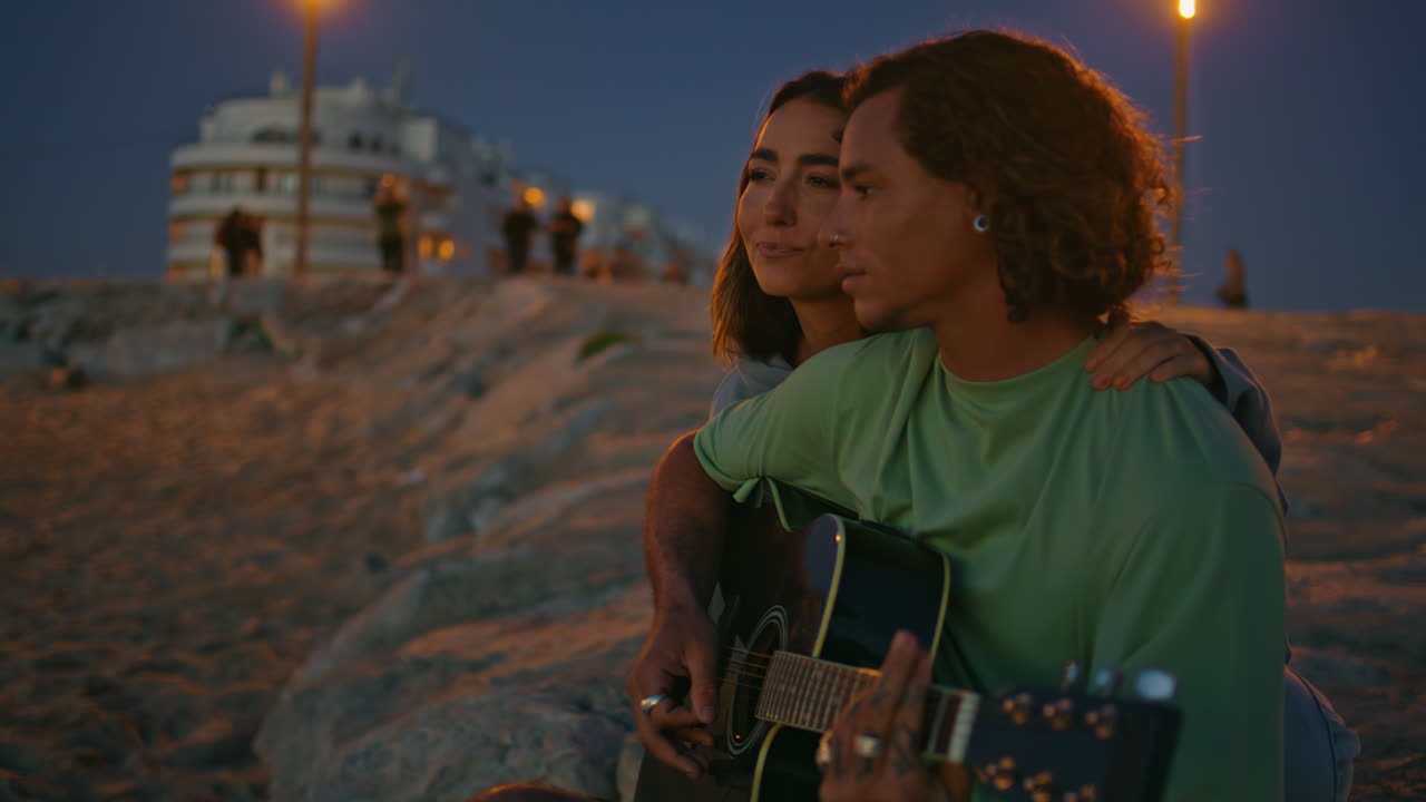 joven toca la música de la guitarra en la noche playa de cerca. adolescentes noche romántica