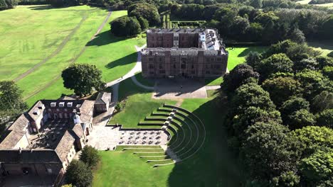 aerial drone captures stunning footage of historic buildings nestled within lush forest in england, uk