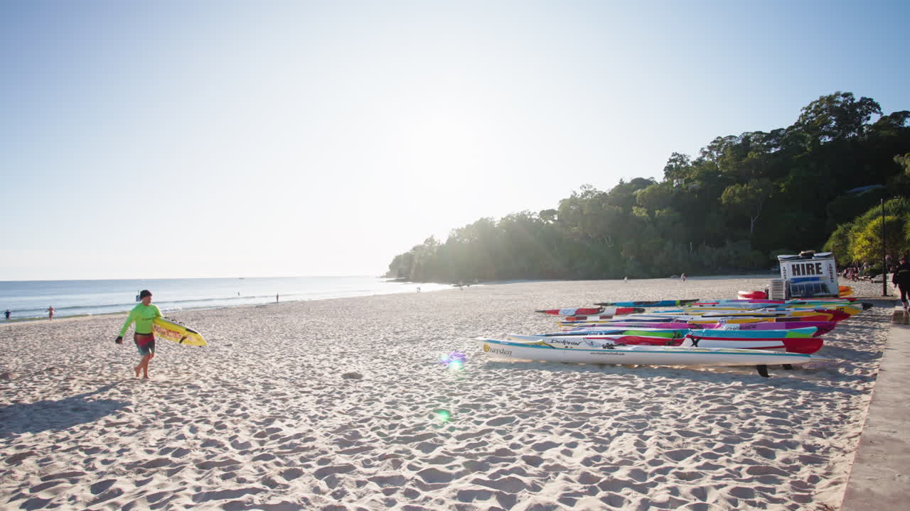 인명구조원이 곶 앞에서 부유물과 서핑 카약을 타고 모래사장을 걷고 있으며, 4k 슬로우 모터인