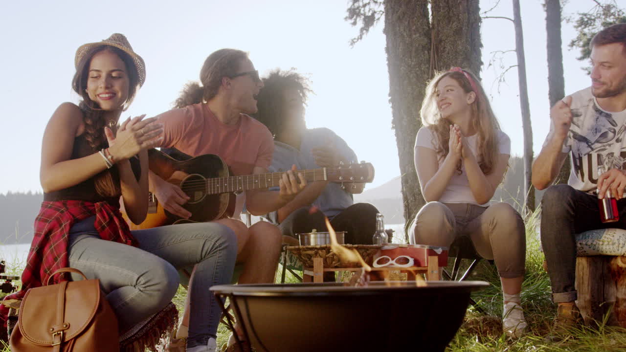 캠프 불에서 노래하는 친구들이 즐기고 있습니다.