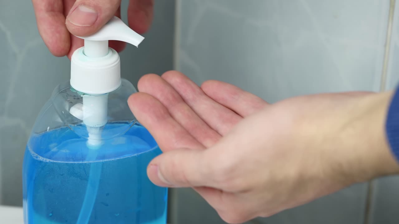 Man hands pours blue liquid soap onto his palm. Corona Virus idea. Close up