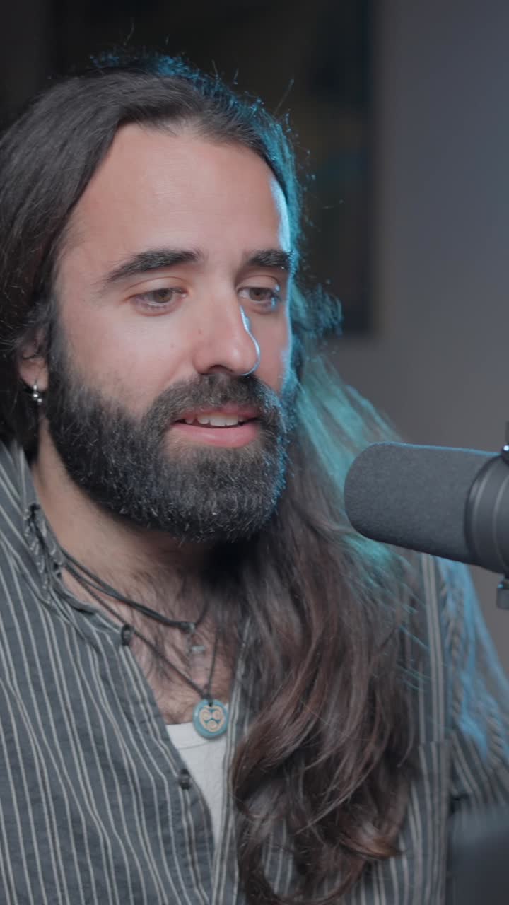 Man with Long Hair and Beard Speaking into a Microphone