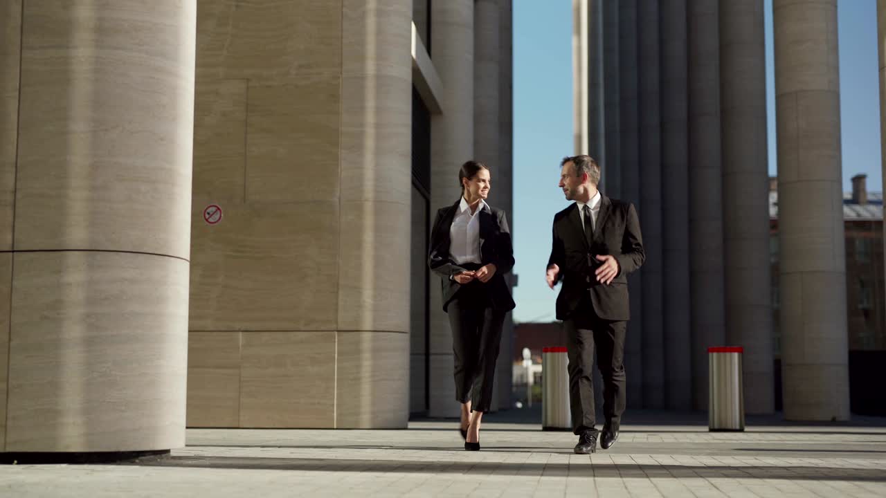 두 명의 사업가, 중년 남성과 공식적인 슈트를 입은 젊은 여성이 함께 거리를 고 이야기하는 전체 길이