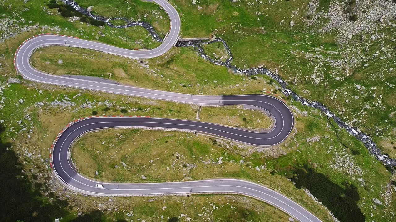 Top down wiev-Drone aerial view over Transfăgărășan, winding road, Balea lake lodges, rocky cliffs and mountain mist.