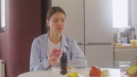 Pregnant-Woman-Sitting-At-Table-Eating-A-Donut-And-Talking-With-Coworker-In-Canteen