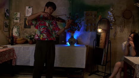 right slider shot of asian male serenading female by playing violin in cafe