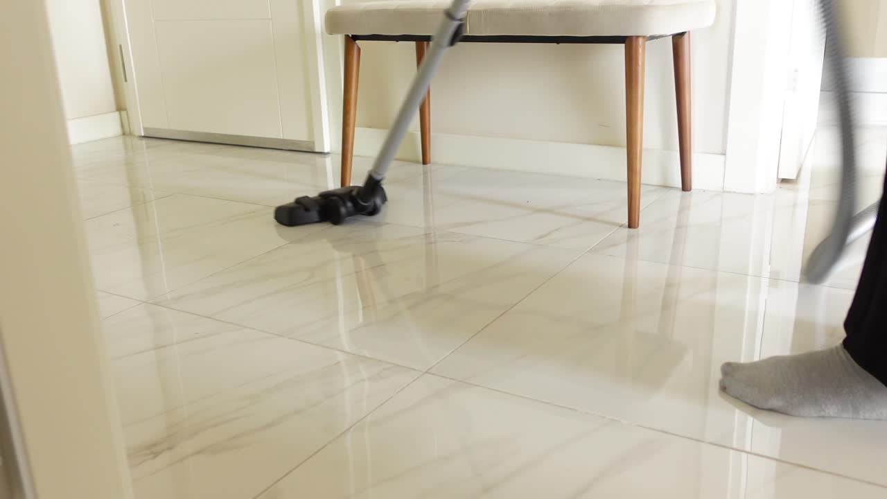 persona aspirando un piso de azulejos