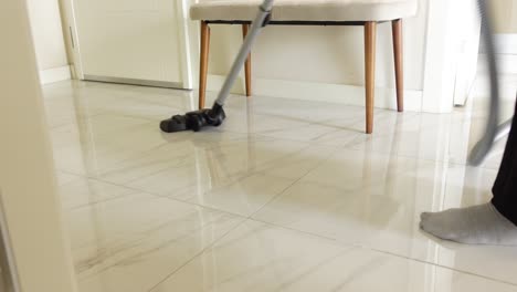 person vacuuming a tiled floor