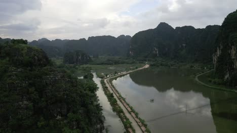 -Beautiful-aeria-shot-of-lonely-road-in-the-middle-of-wetlands-in-the-mountains-of-Nin-Bihn,-Vietnam