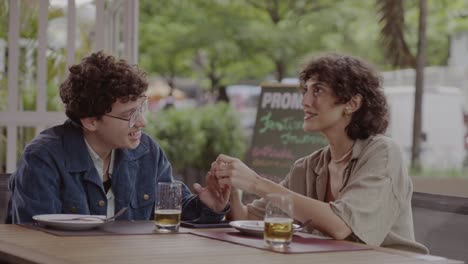 two people chatting and holding hands at an outdoor cafe