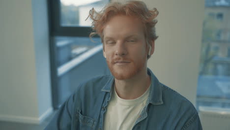 portrait of young handsome red haired man smiling and looking at camera indoors