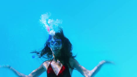 pretty brunette swimming underwater into pool with snorkel