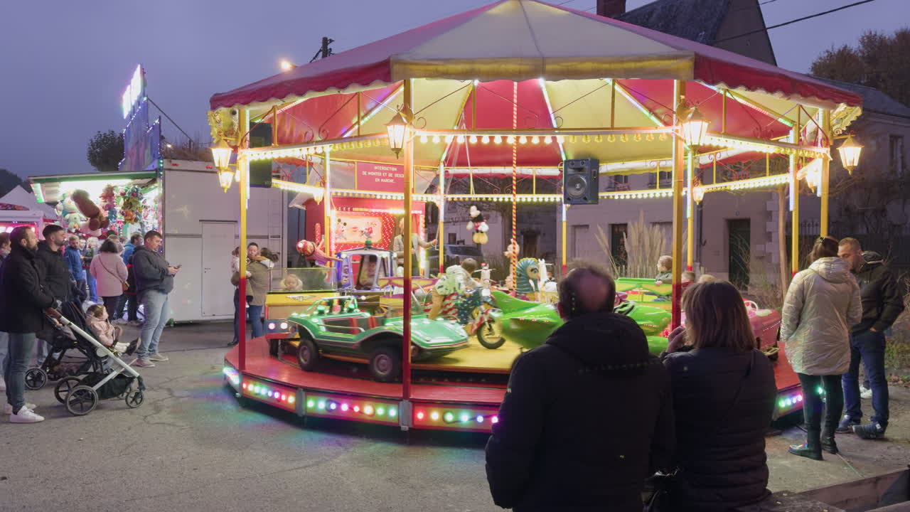 Colorful carousel spinning at night as families watch at a local fair in Montrichard Val de Cher