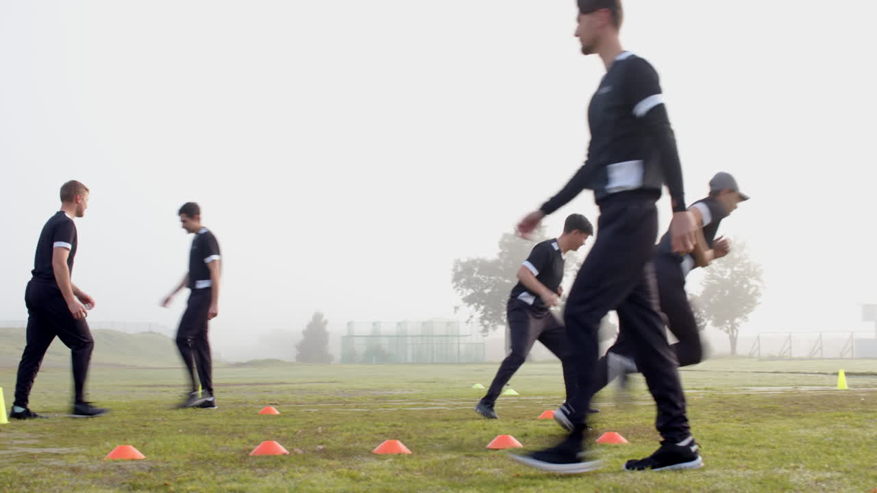 Training on field, men running drills with cones for cricket practice