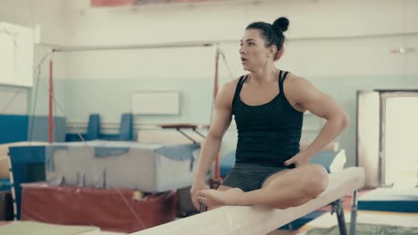 chica atlética joven en un gimnasio sentada en una barra y descansando después del entrenamiento