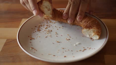 breaking a simit (turkish bagel) on a plate