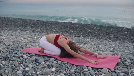 mujer practicando yoga en una playa