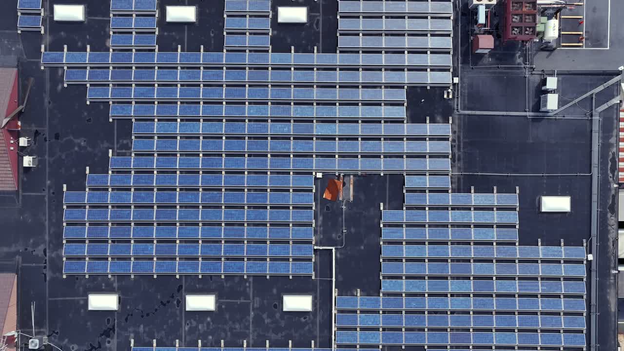 Solar panel units on roof of warehouse building with rotating Ventilator. Aerial top down shot. Industrial area in american town. Production of cheap green energy.