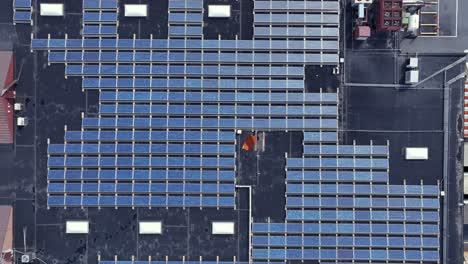 solar panel units on roof of warehouse building with rotating ventilator. aerial top down shot. industrial area in american town. production of cheap green energy.