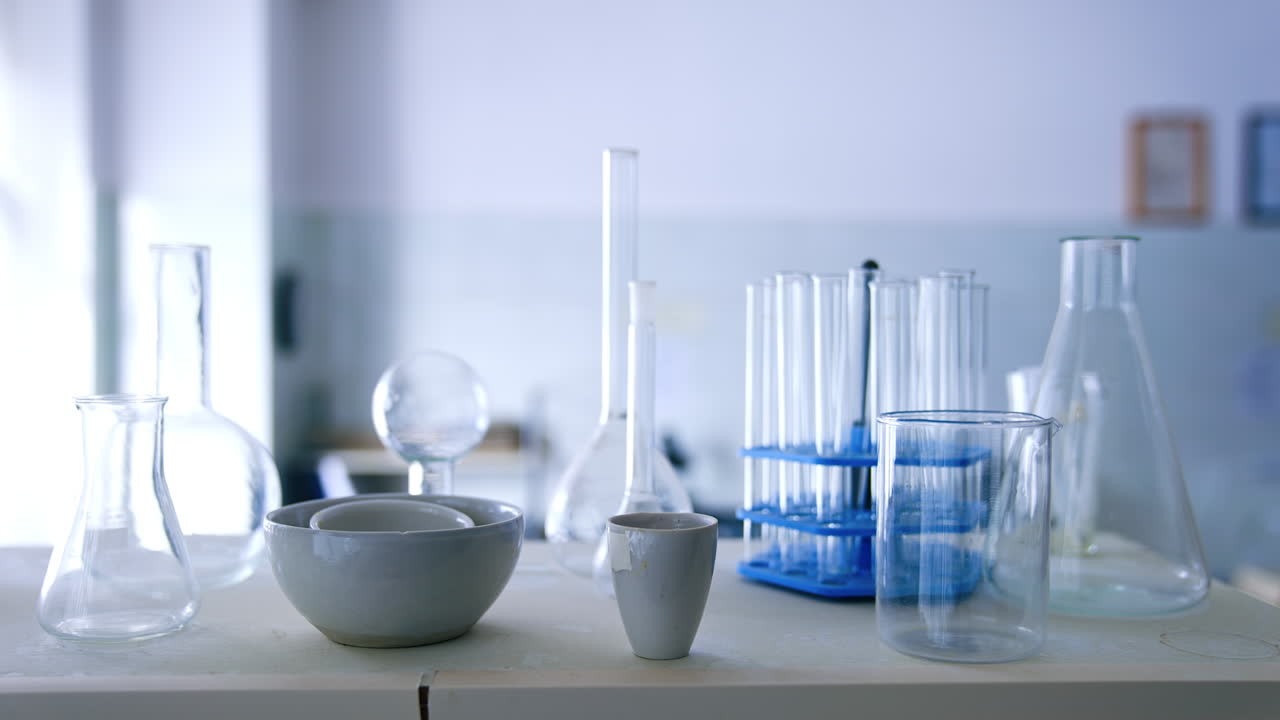 Glassware for science lab experiments. Beakers and flasks on the desk. Blurred backdrop.